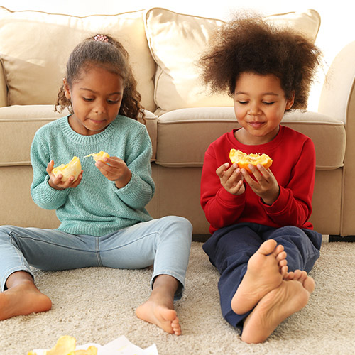 Two kids eating oranges